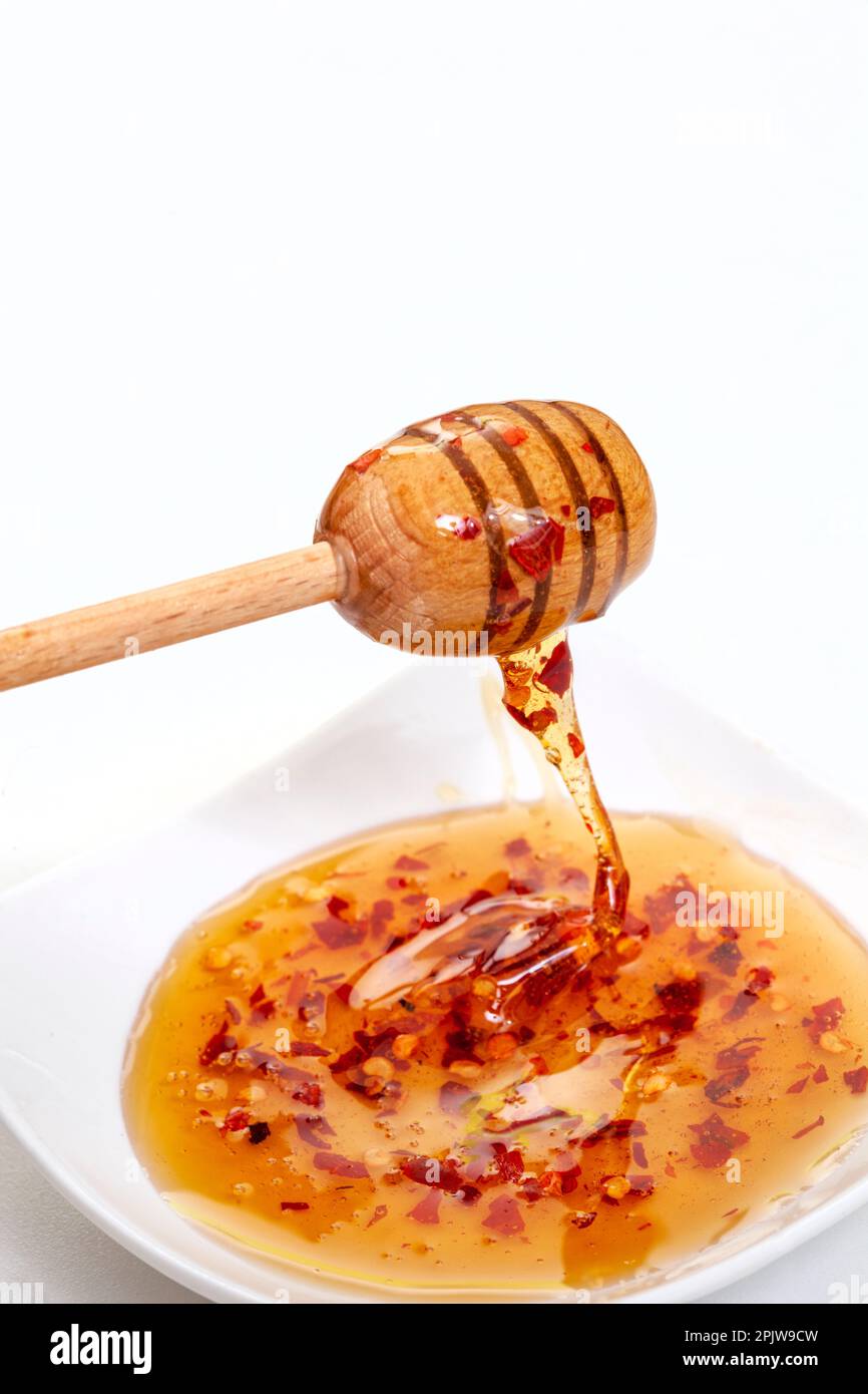 Hot honey or chili honey in white bowl with honey dipper on white Stock