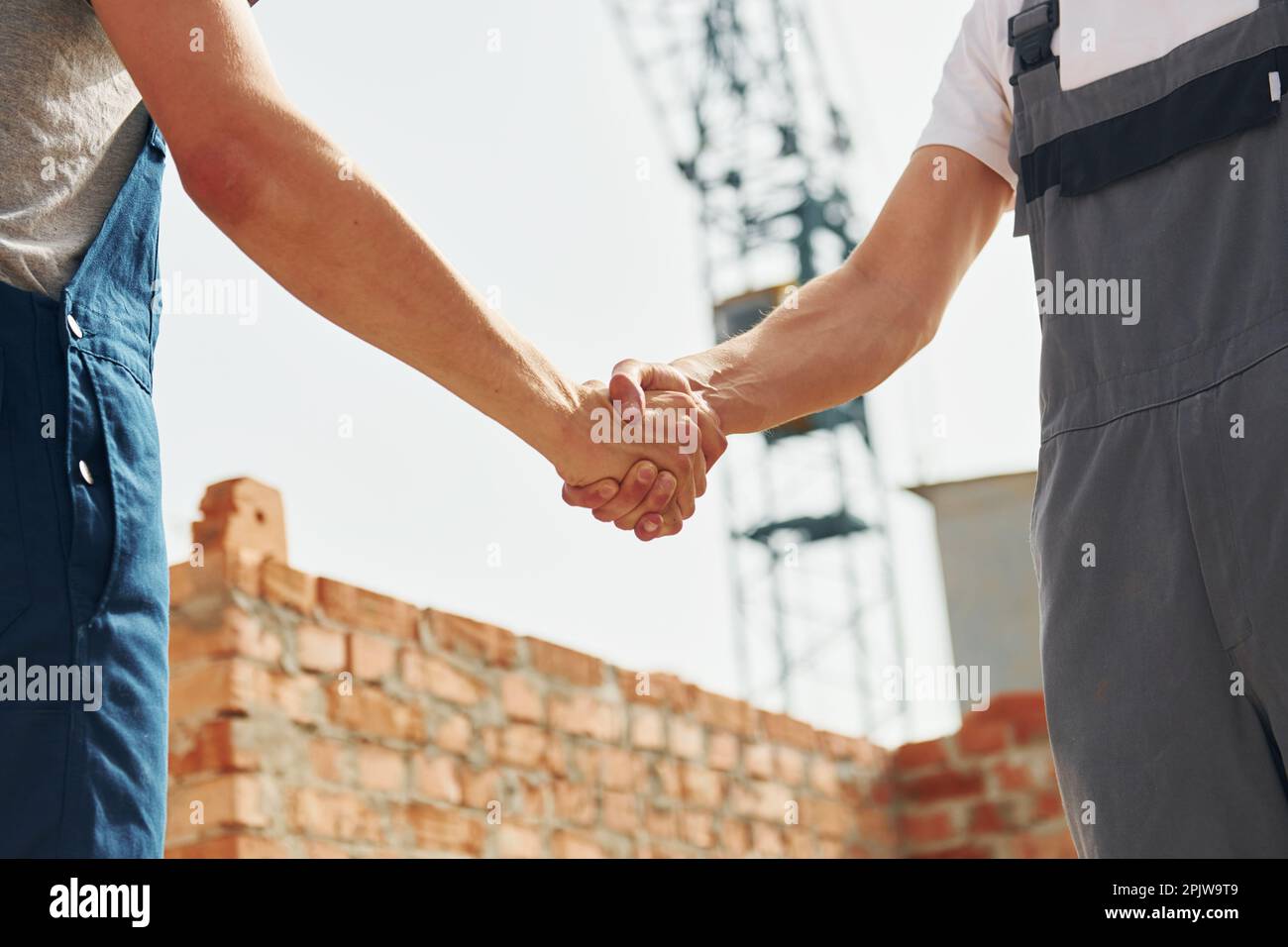 Doing handshake. Two construction workers is together at the building Stock Photo