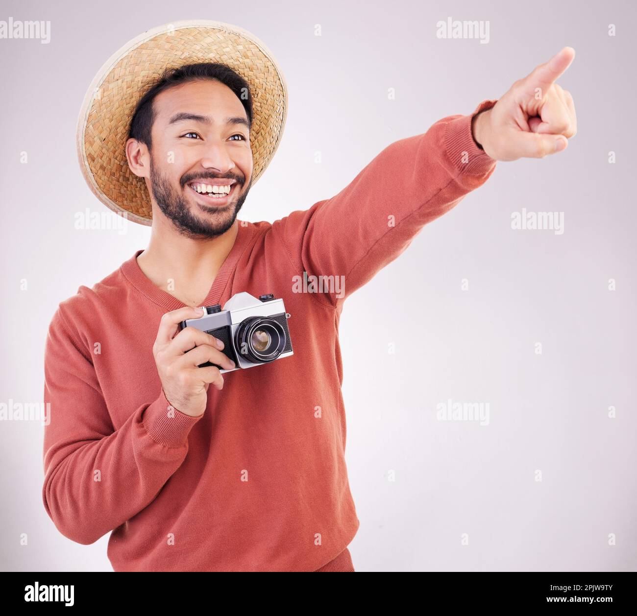 Travel, camera and excited man pointing at view in studio on holiday with adventure, fun and white background. Smile, discovery and happy tourist on Stock Photo