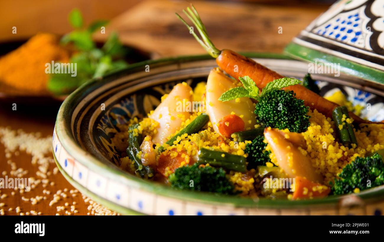 Colorful Moroccan tagine with curried cous cous with calamari, broccoli and other vegetables. Stock Photo
