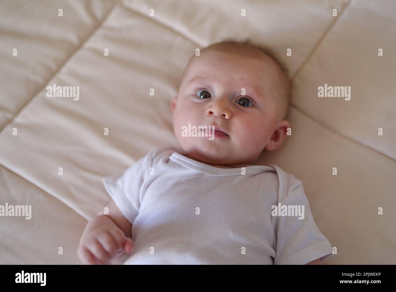 A 3 month old baby boy laying on a bed Stock Photo