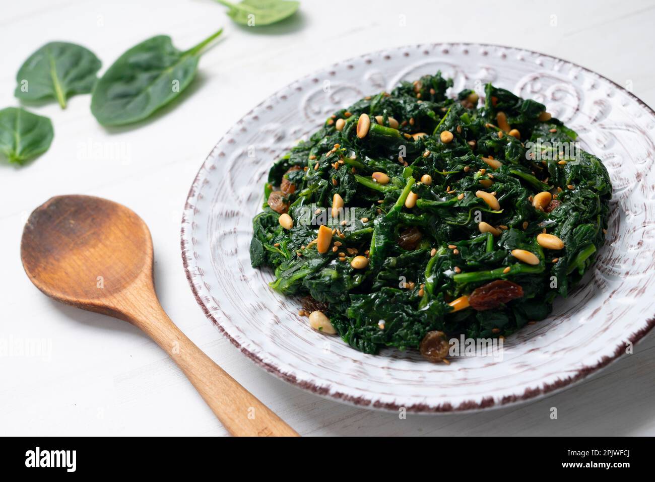 Spinach cooked in a pan with raisins, pine nuts and garlic. Stock Photo
