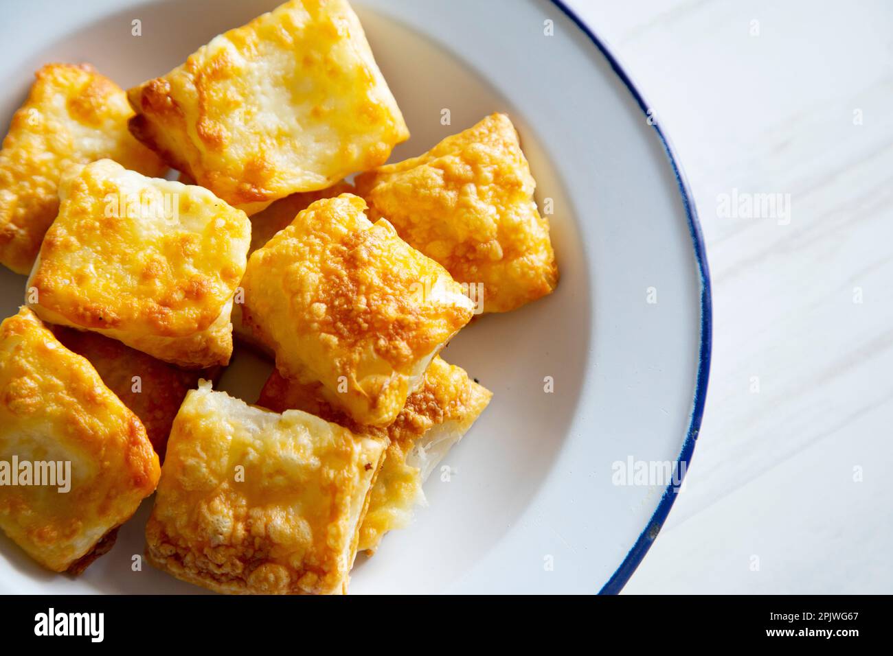 Small, square puff pastries with gratin cheese. Stock Photo