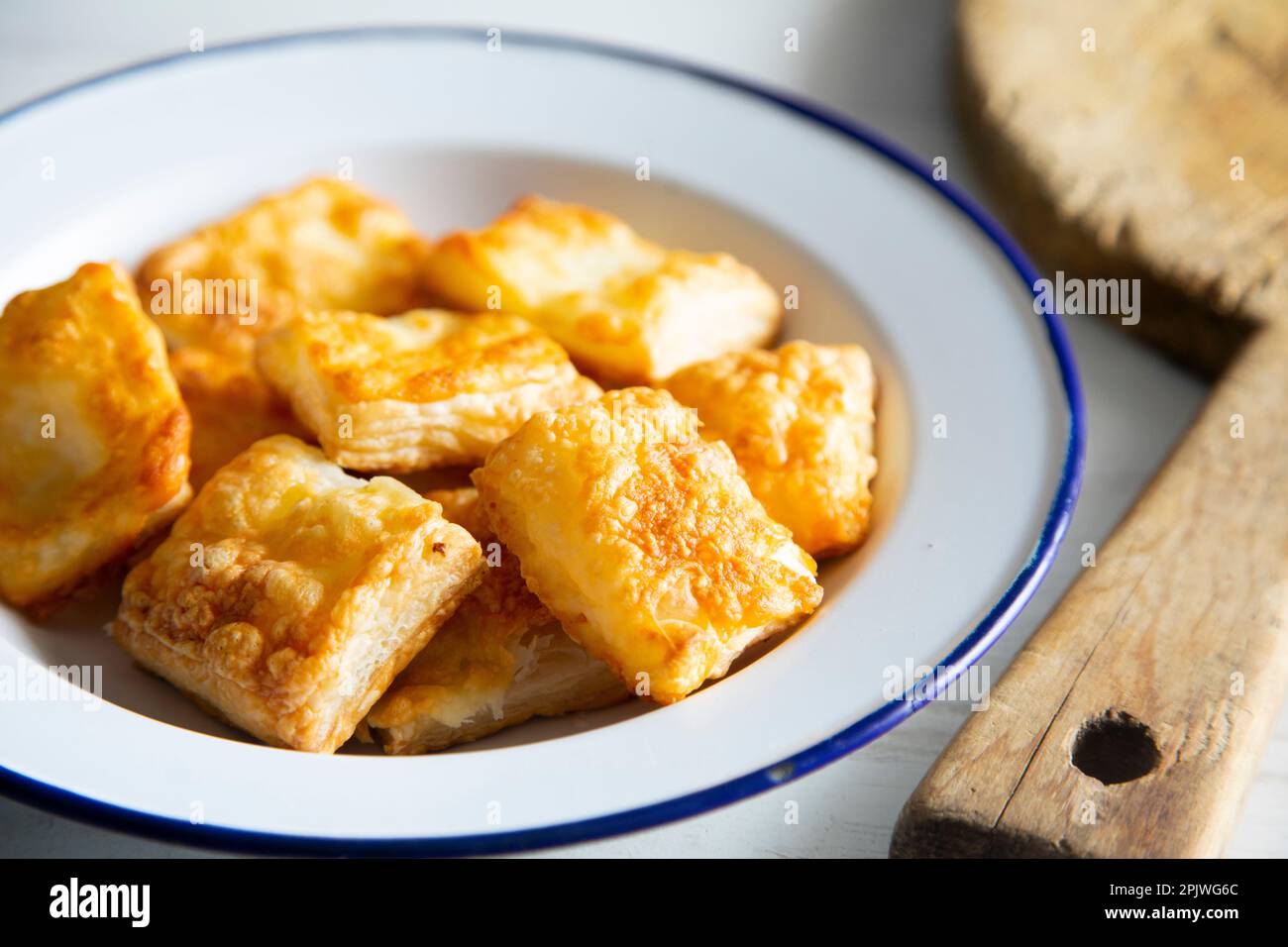 Small, square puff pastries with gratin cheese. Stock Photo