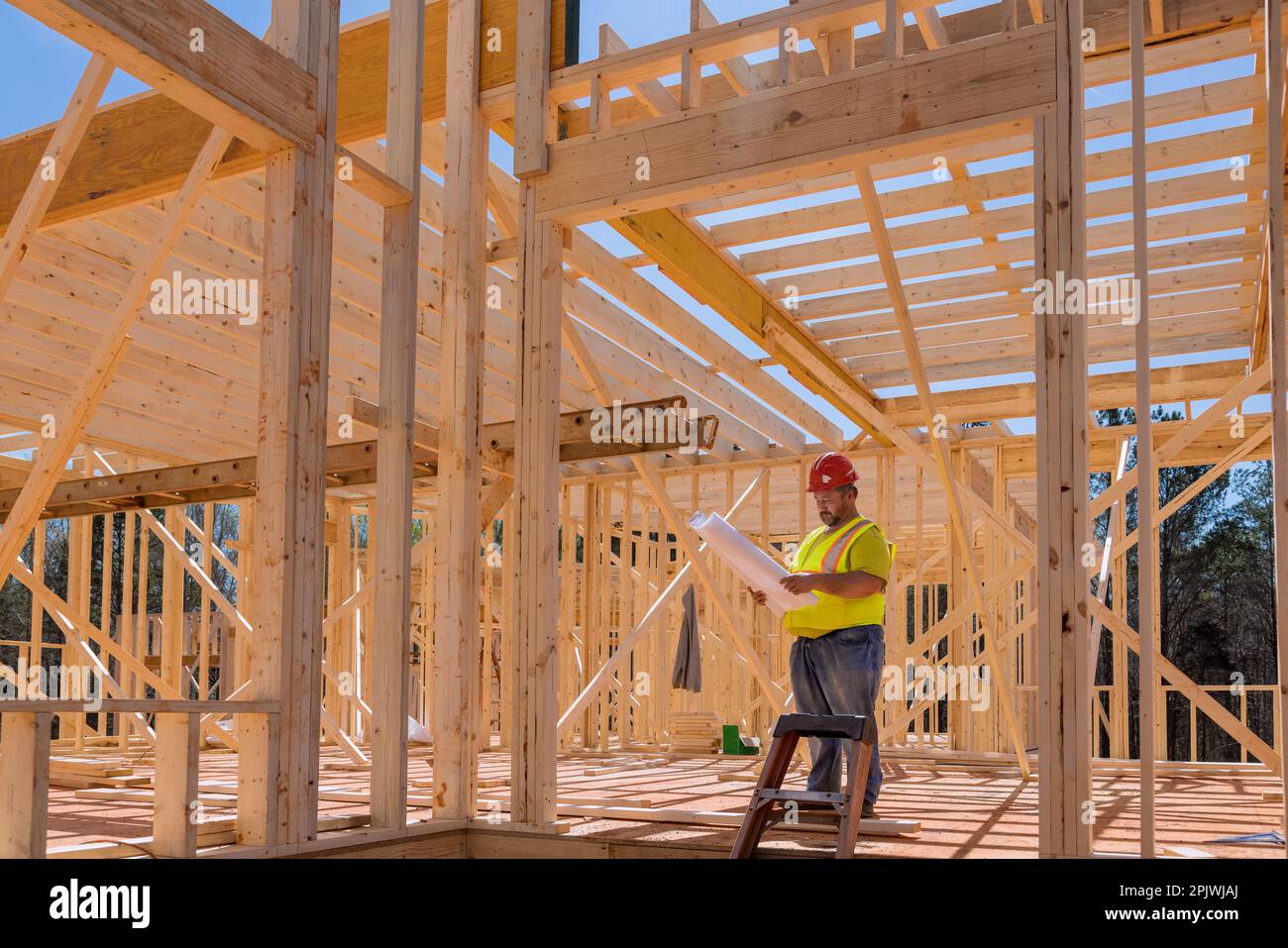 An engineer checking quality of wooden frame using blueprint plan architecture during construction phase project Stock Photo