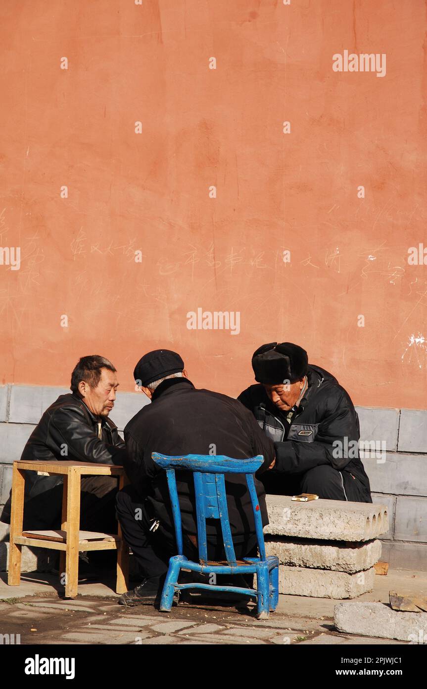 Mah jong players against an orange wall. Henan, near Luoyang, China Stock Photo