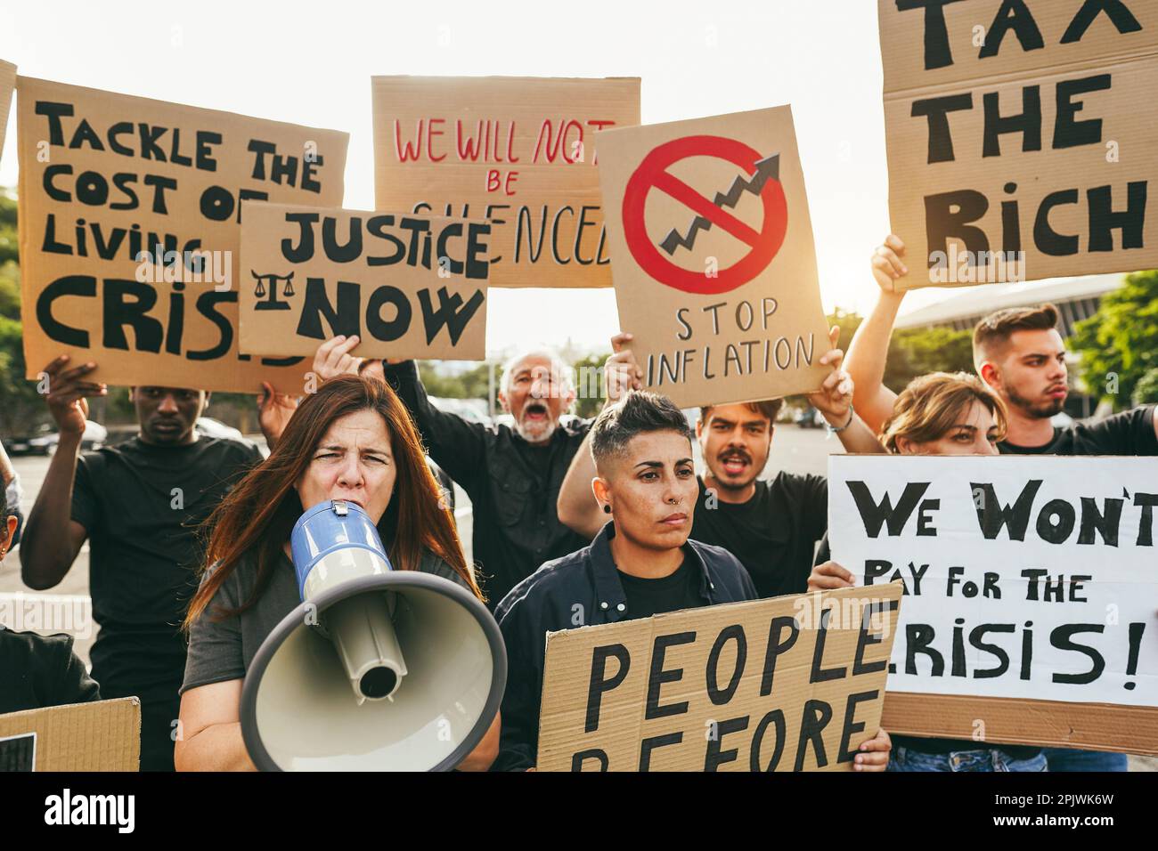 Crowd of multiracial people protest against inflation and financial crisis - Protesters marching for rise cost of living - Focus on woman with megapho Stock Photo