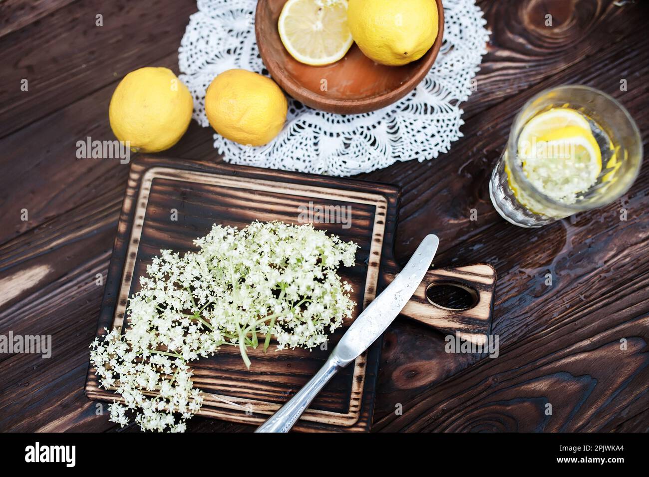 Grinding lemon and black elderberry on a cutting board to make an herbal drink or medicine for healing at home from syrup from elderberry flowers. Stock Photo