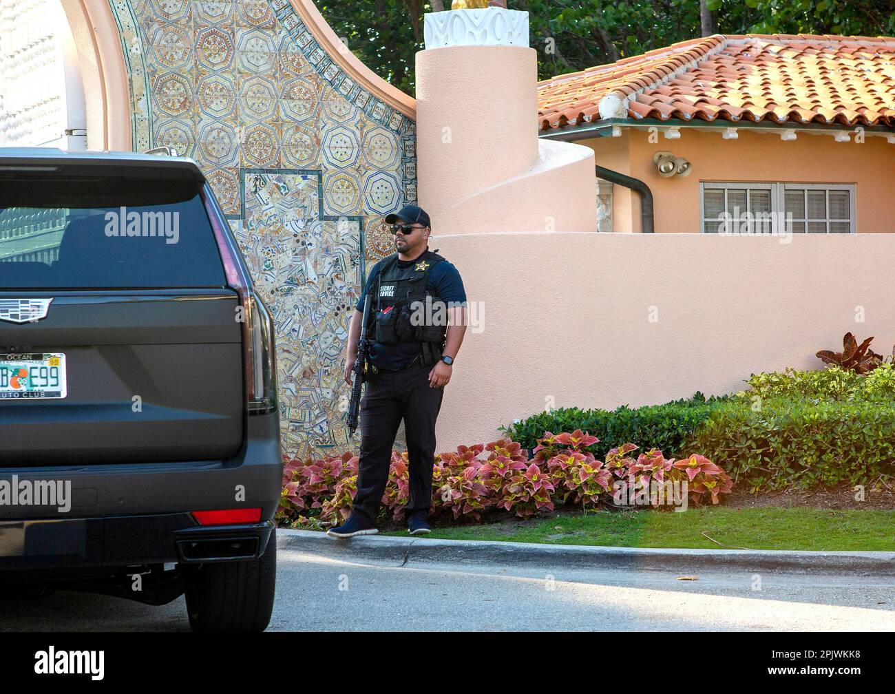 Armed Secret Service agent guards the entrance to Mar-a-Lago.Former President Donald Trump arrives at Palm Beach International Airport as supporters w Stock Photo