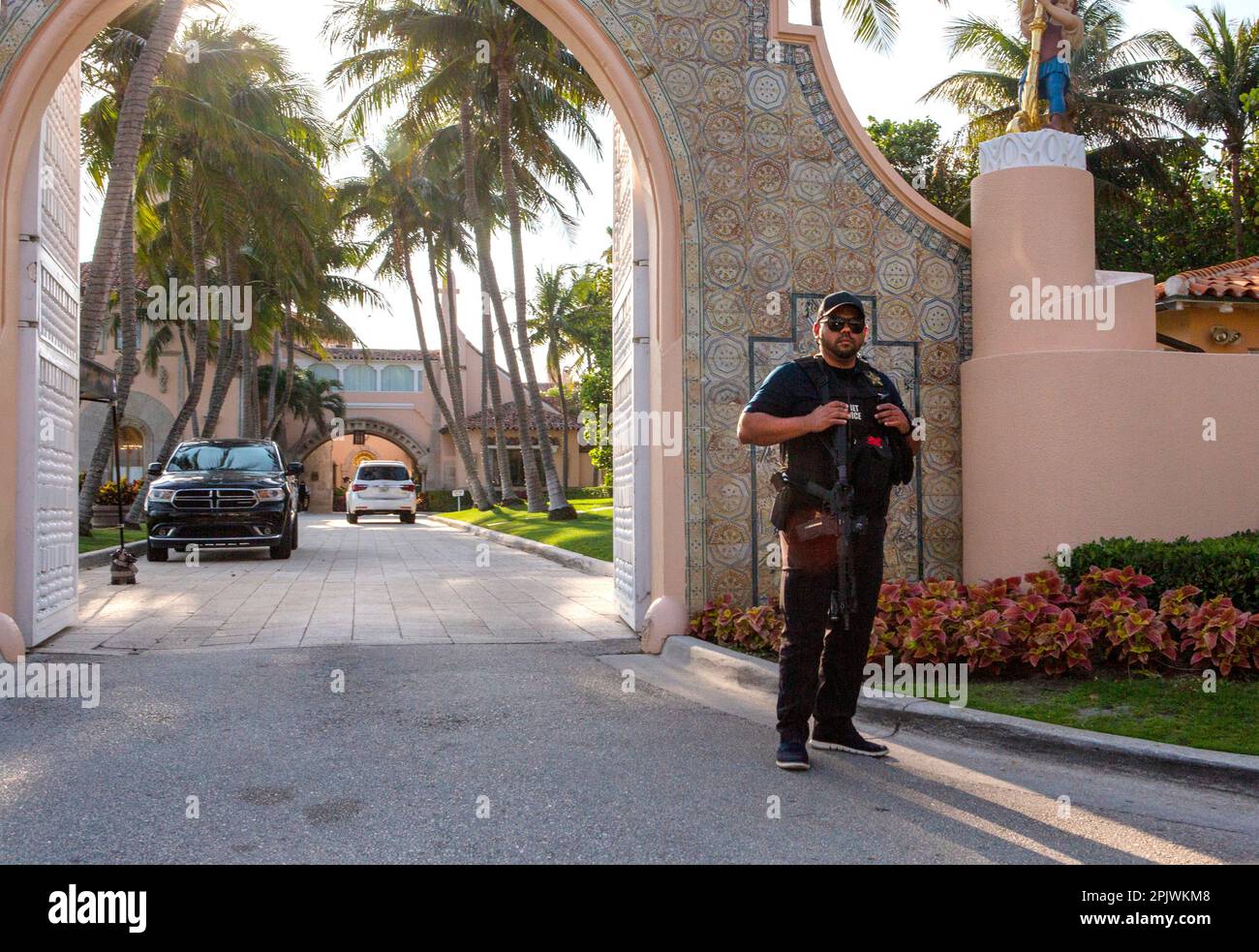 Armed Secret Service agent guards the entrance to Mar-a-Lago. Former President Donald Trump arrives at Palm Beach International Airport as supporters Stock Photo