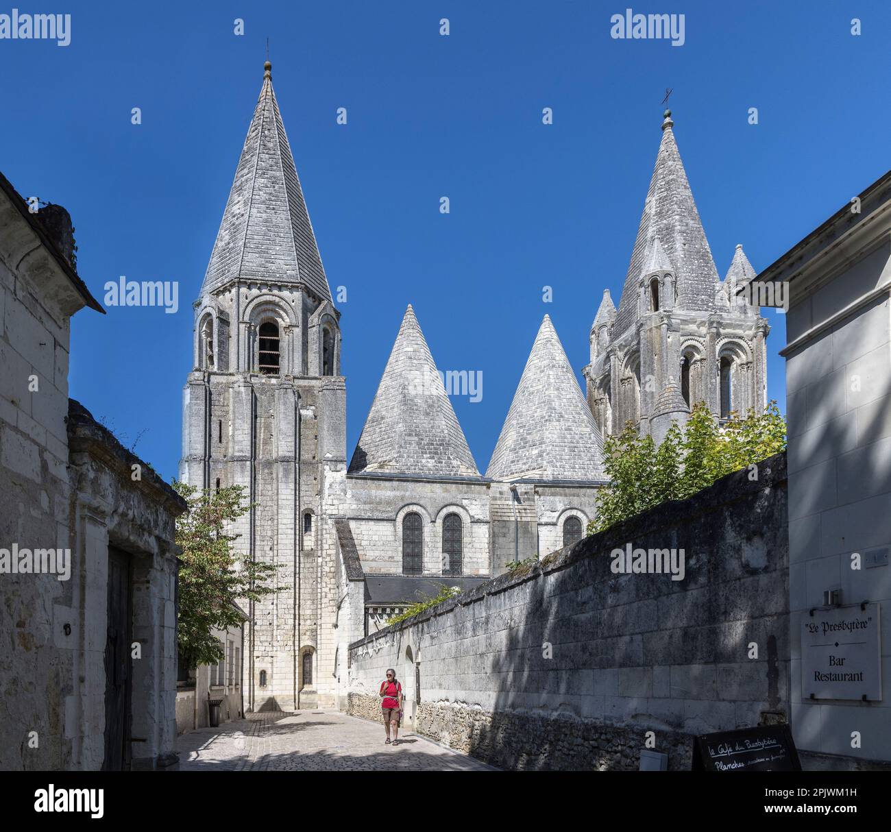 Person walking in street past the church of St Ours, Loches, Indre-et-Loire, central France Stock Photo