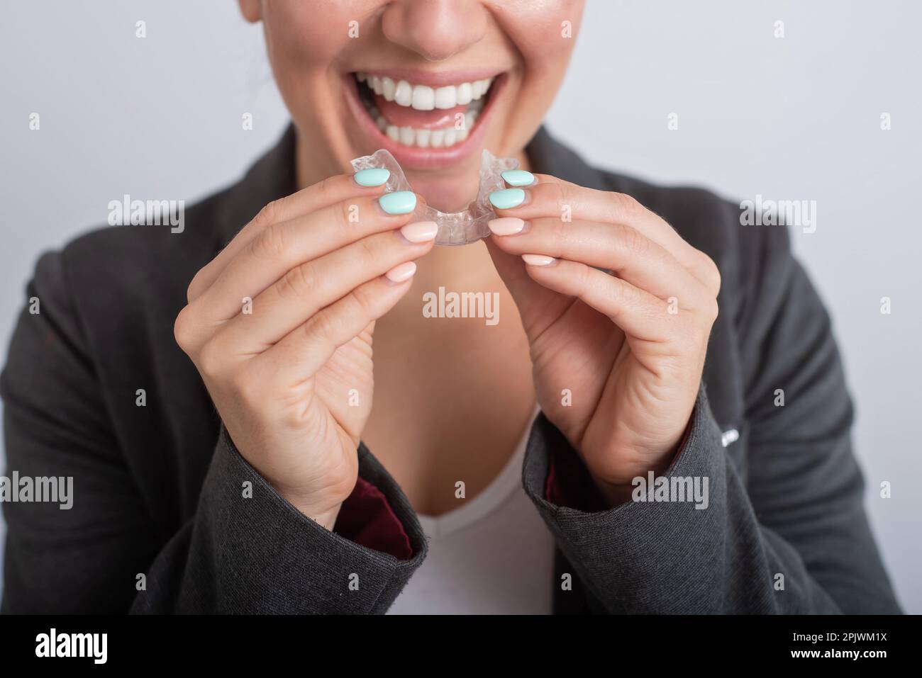 Close-up of a woman putting on transparent plastic retainers. The girl ...