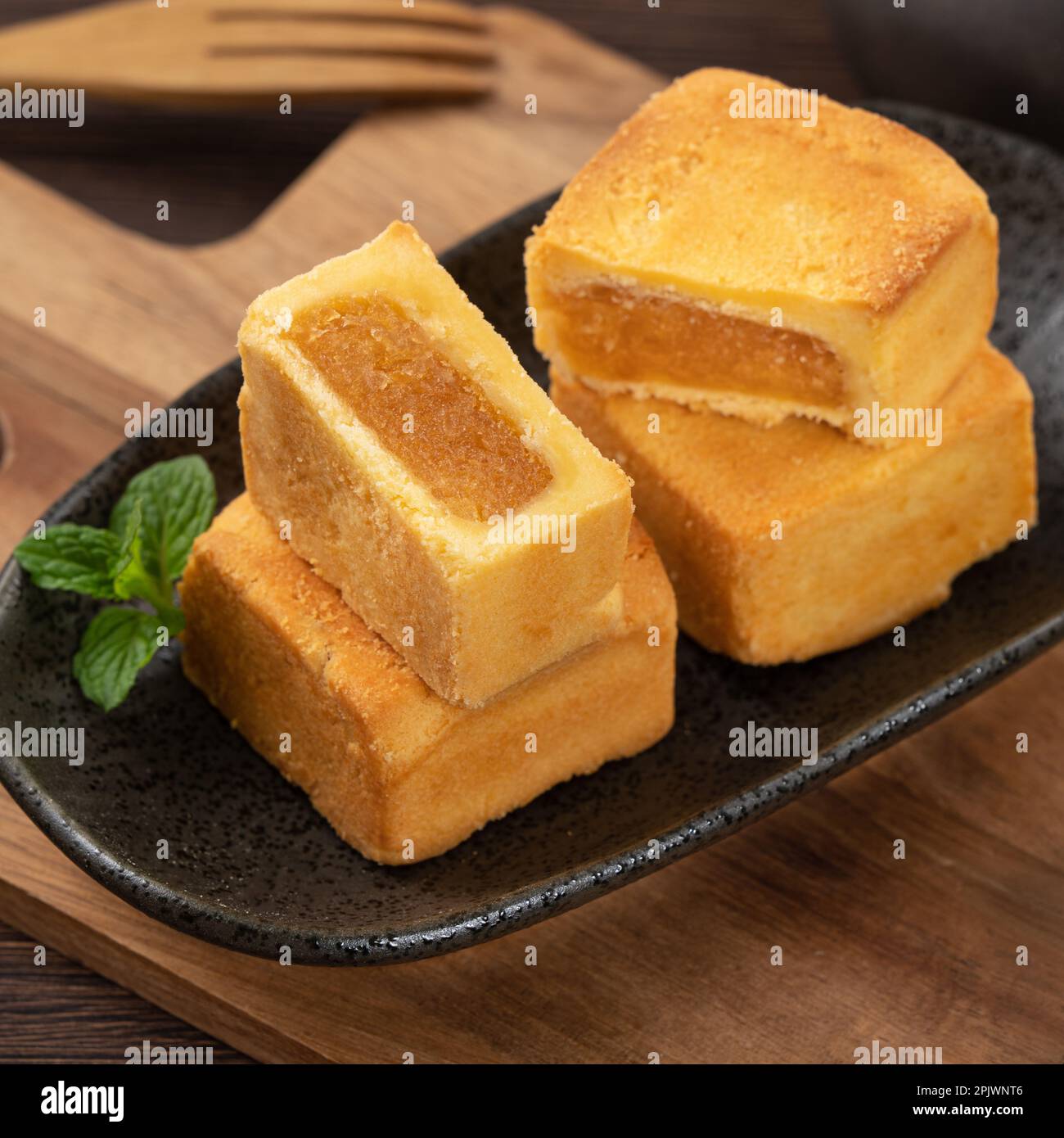 Delicious Taiwanese pineapple cake pastry dessert in a plate on wooden table background with hot tea. Stock Photo