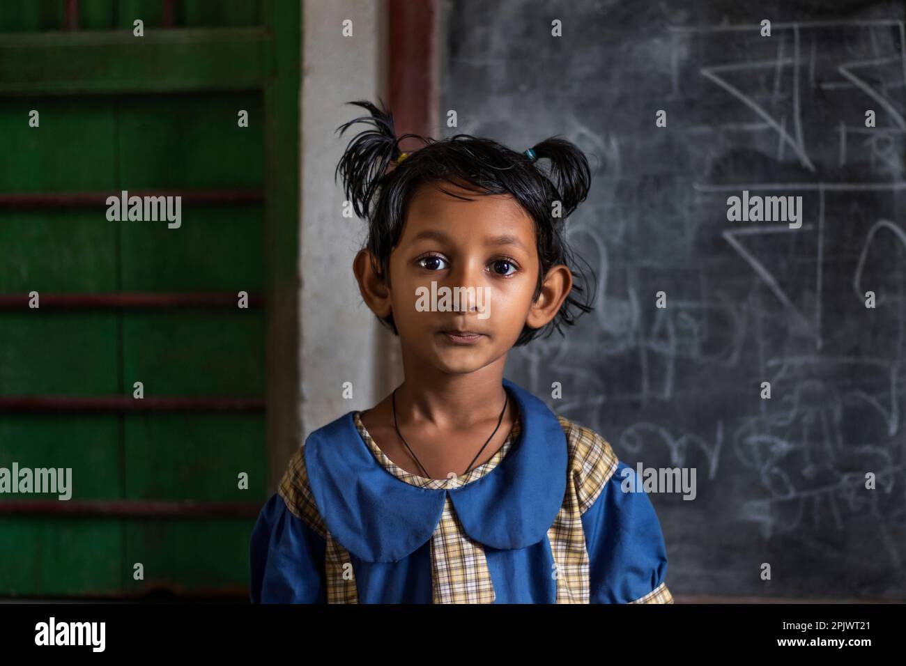School girl standing by the blackboard at school Stock Photo