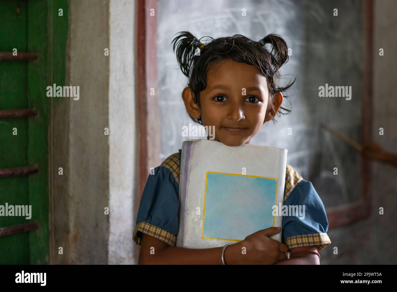 School girl holding book standing at school Stock Photo - Alamy