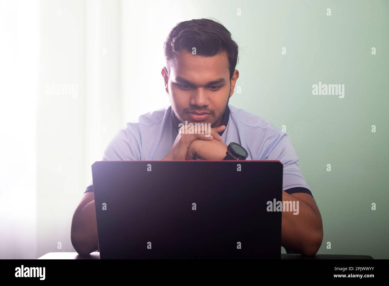College student talking on a video call while writing his assignment ...