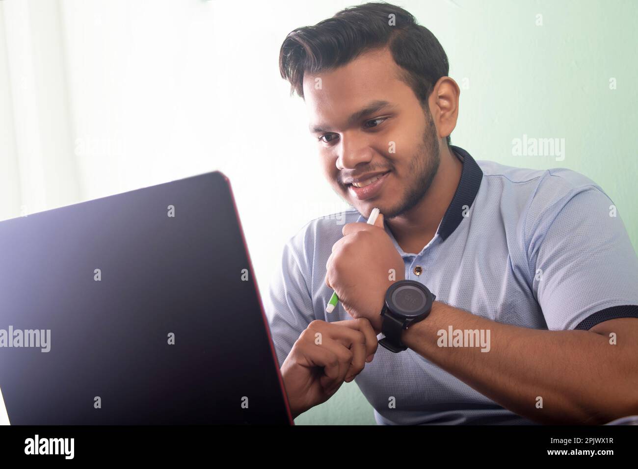 College student talking on a video call while writing his assignment Stock Photo