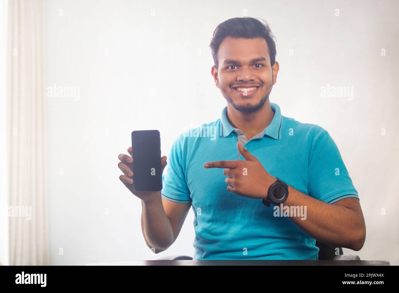Portrait of a young man showing mobile phone in his hand Stock Photo