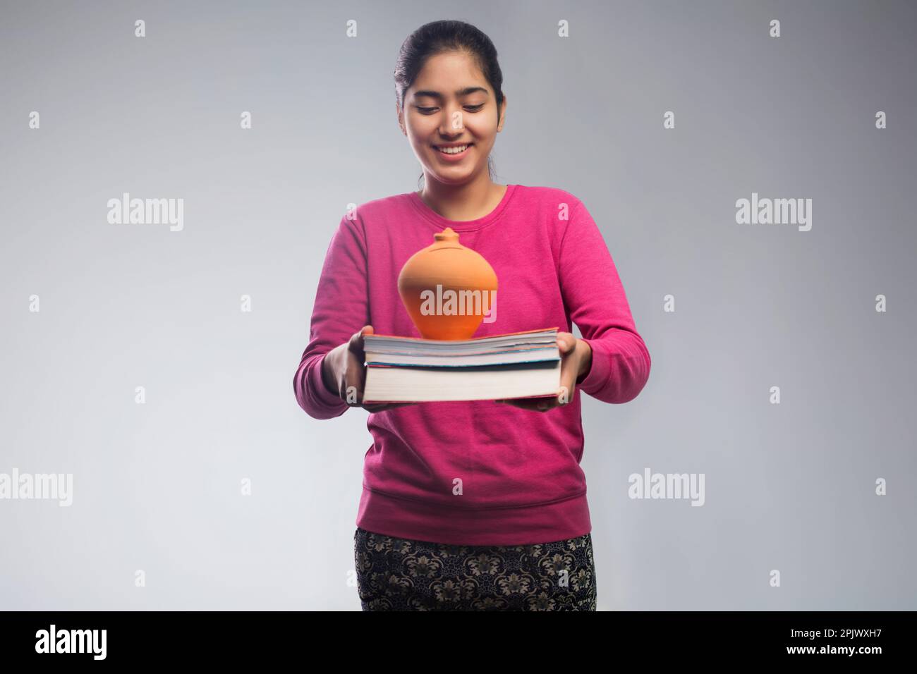 young college student holding stack of books with a money bank Stock Photo
