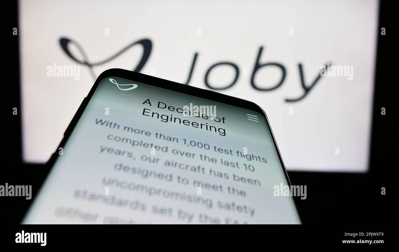 Mobile phone with web page of American eVTOL company Joby Aviation on screen in front of business logo. Focus on top-left of phone display. Stock Photo