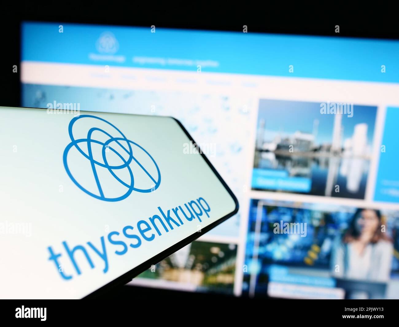 Mobile phone with logo of German conglomerate ThyssenKrupp AG on screen in front of company website. Focus on center-right of phone display. Stock Photo