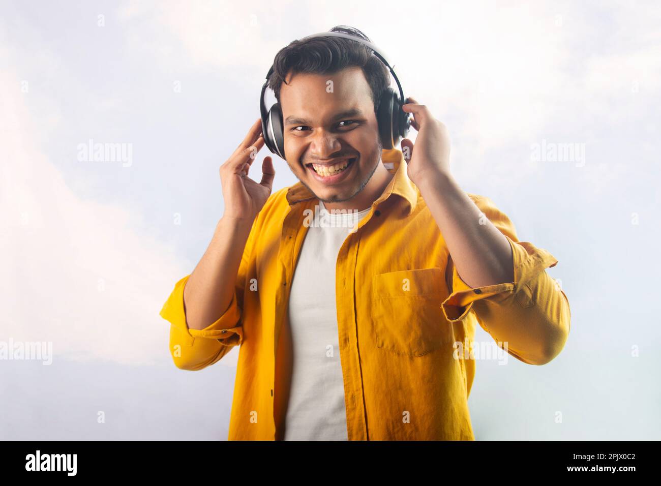 Portrait of a happy young man listening music on headphones Stock Photo