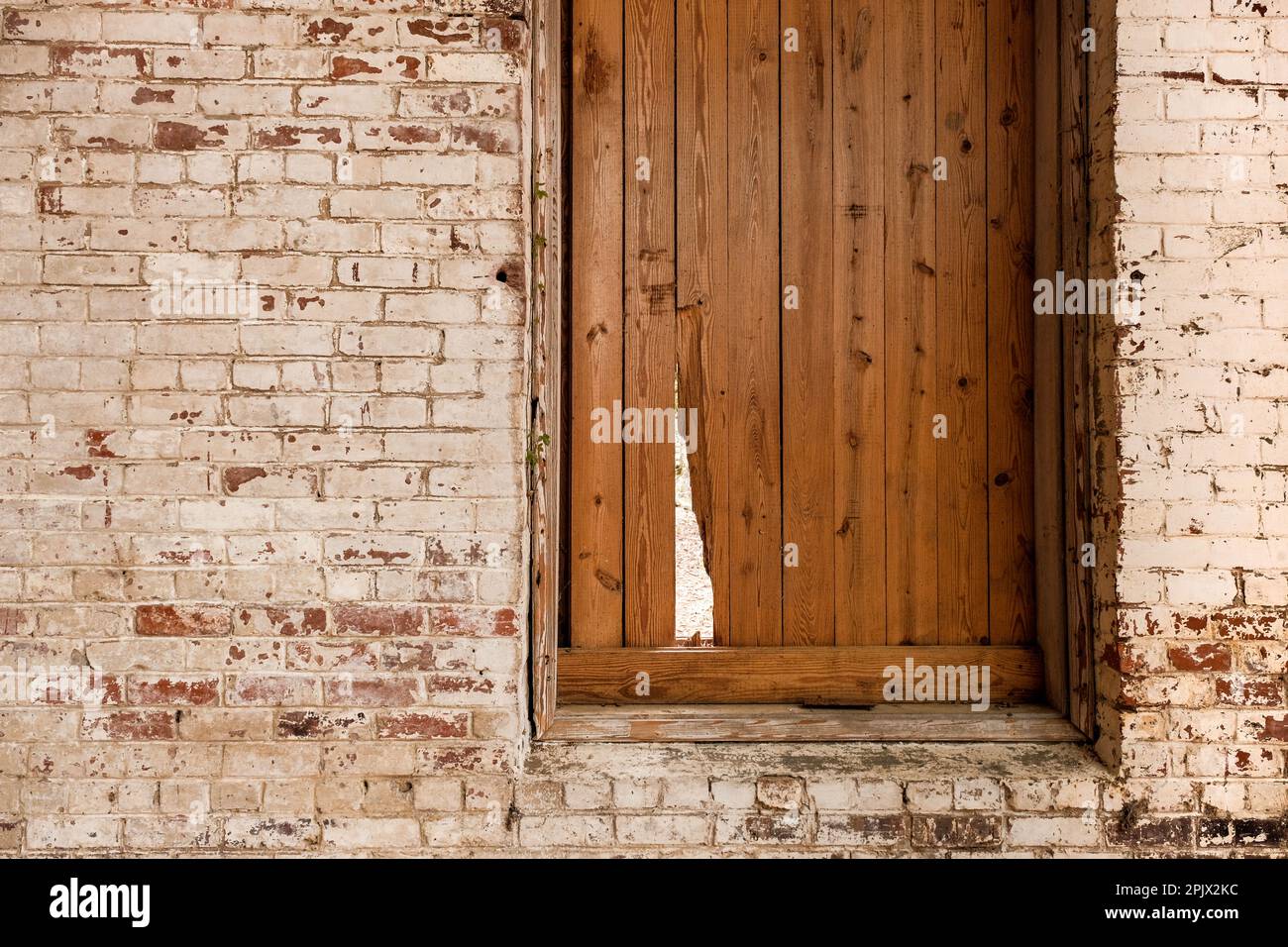 Shuttered window with break in shutter and old white washed brick wall. Stock Photo