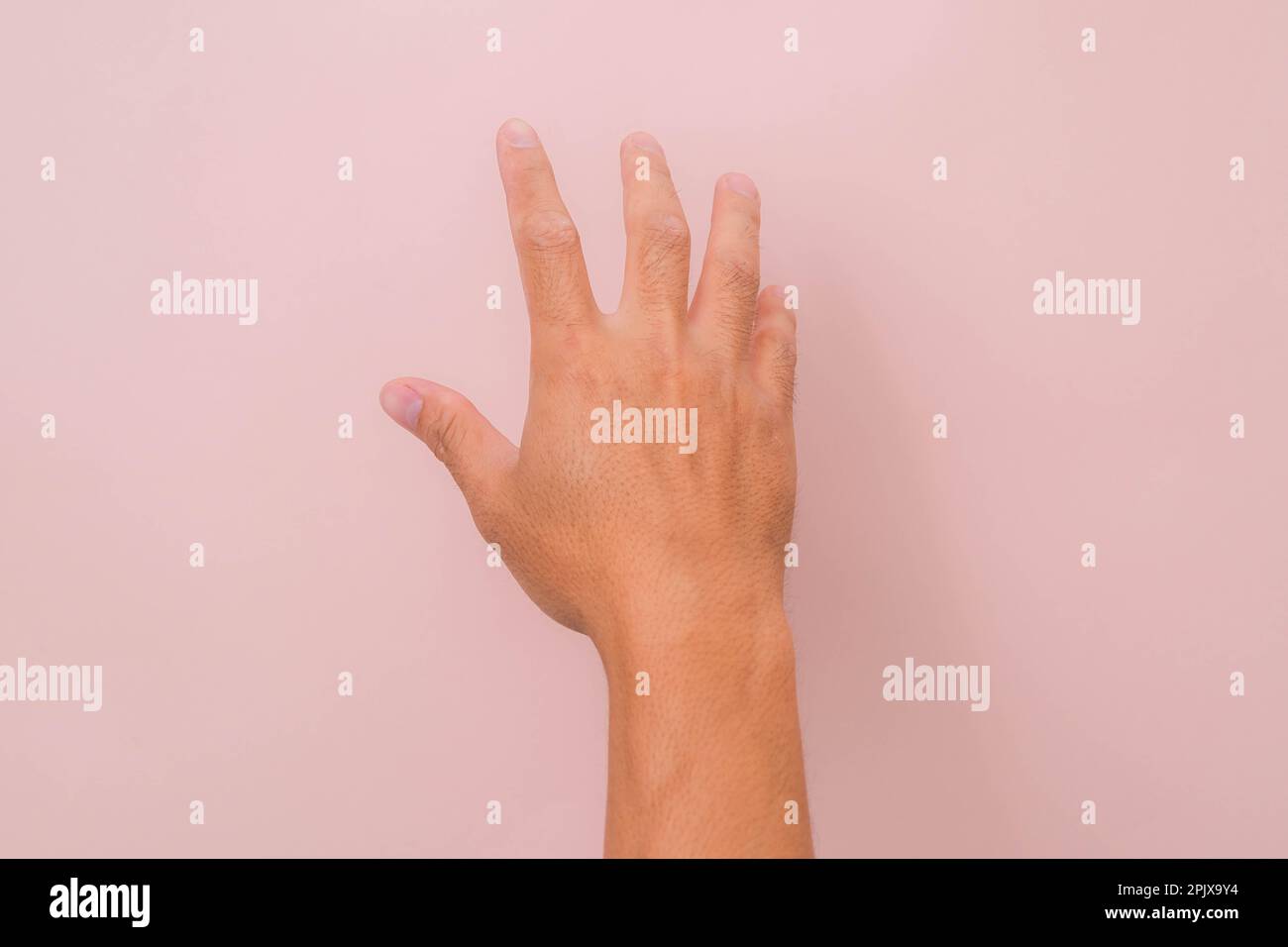 Close up of male hand reaching out ready to help or receive isolated on pink background. Helping hand outstretched for salvation. Stock Photo