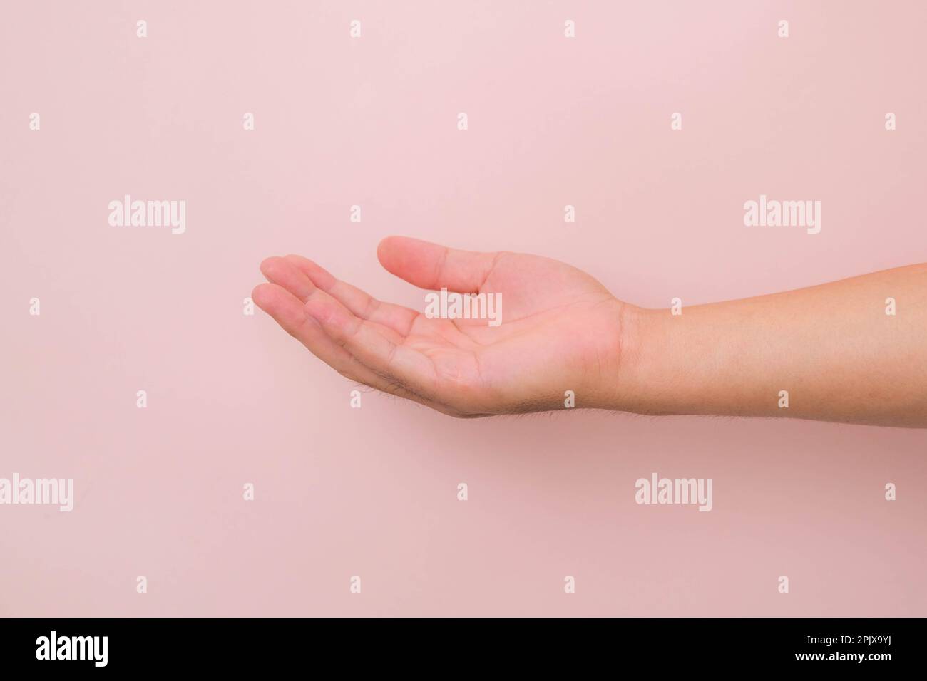 Close up male hand reaching out ready to help or receive isolated on pink background. Helping hand outstretched for salvation. Stock Photo