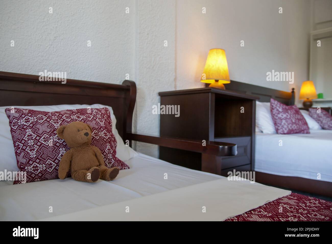 Retro bedroom style with red pattern pillows and brown teddy bear on bed Stock Photo