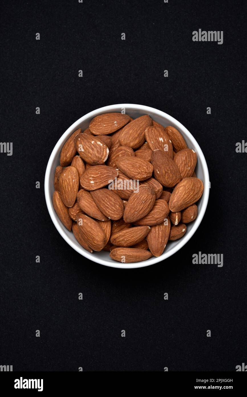 Almonds in a white ceramic bowl. Delicious almonds nuts close-up. Stock Photo