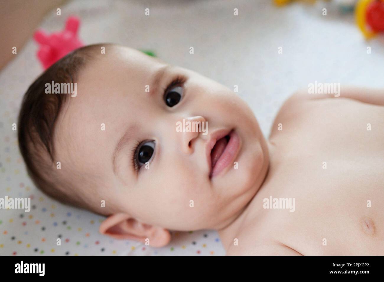 Happy newborn baby makes a funny face. Portrait of a crawling baby