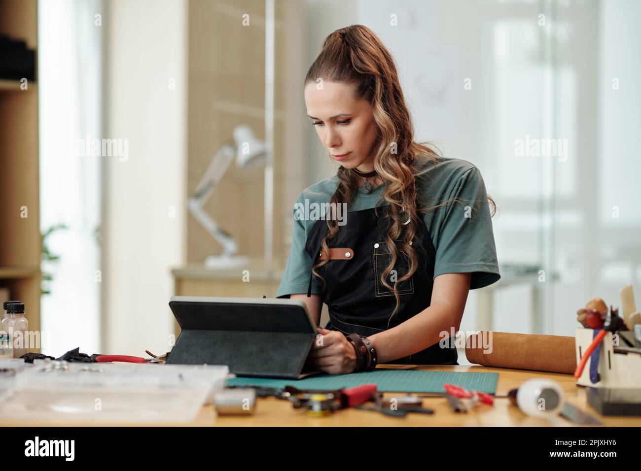 Leather worker checking e-mails and orders from clients on tablet computer Stock Photo