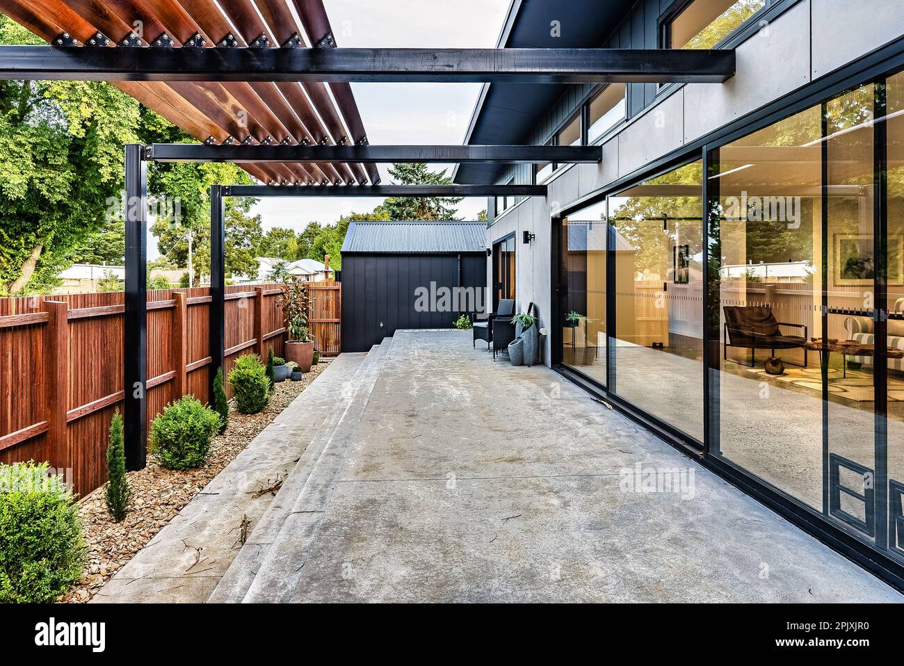 An outdoor patio area with a stone deck provides shade and seating for relaxing Stock Photo