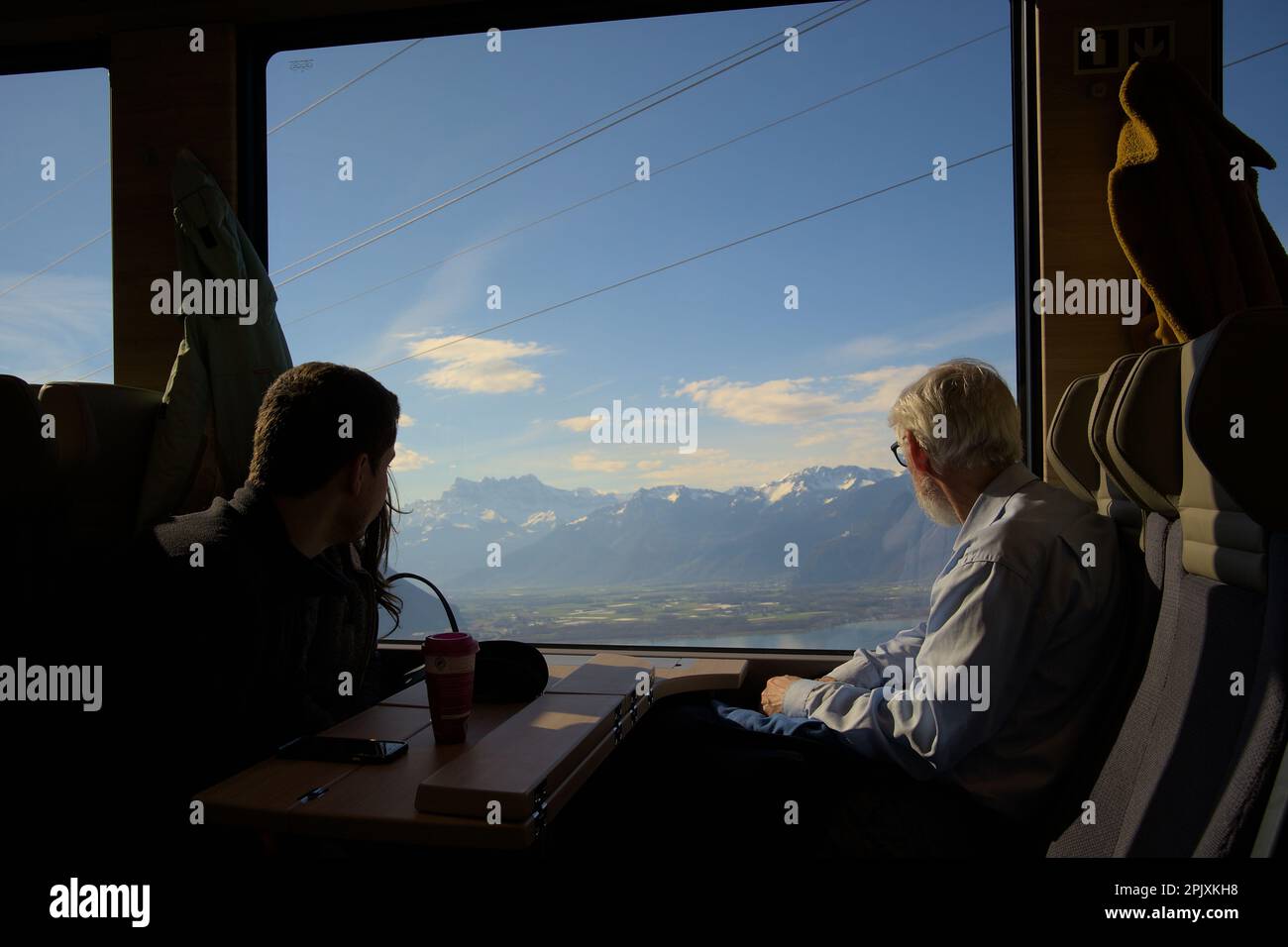 Old man and a couple enjoying the view of the snowy mountains and the lake Geneva in a train from Montreux to Gstaad by Golden Pass Express Stock Photo