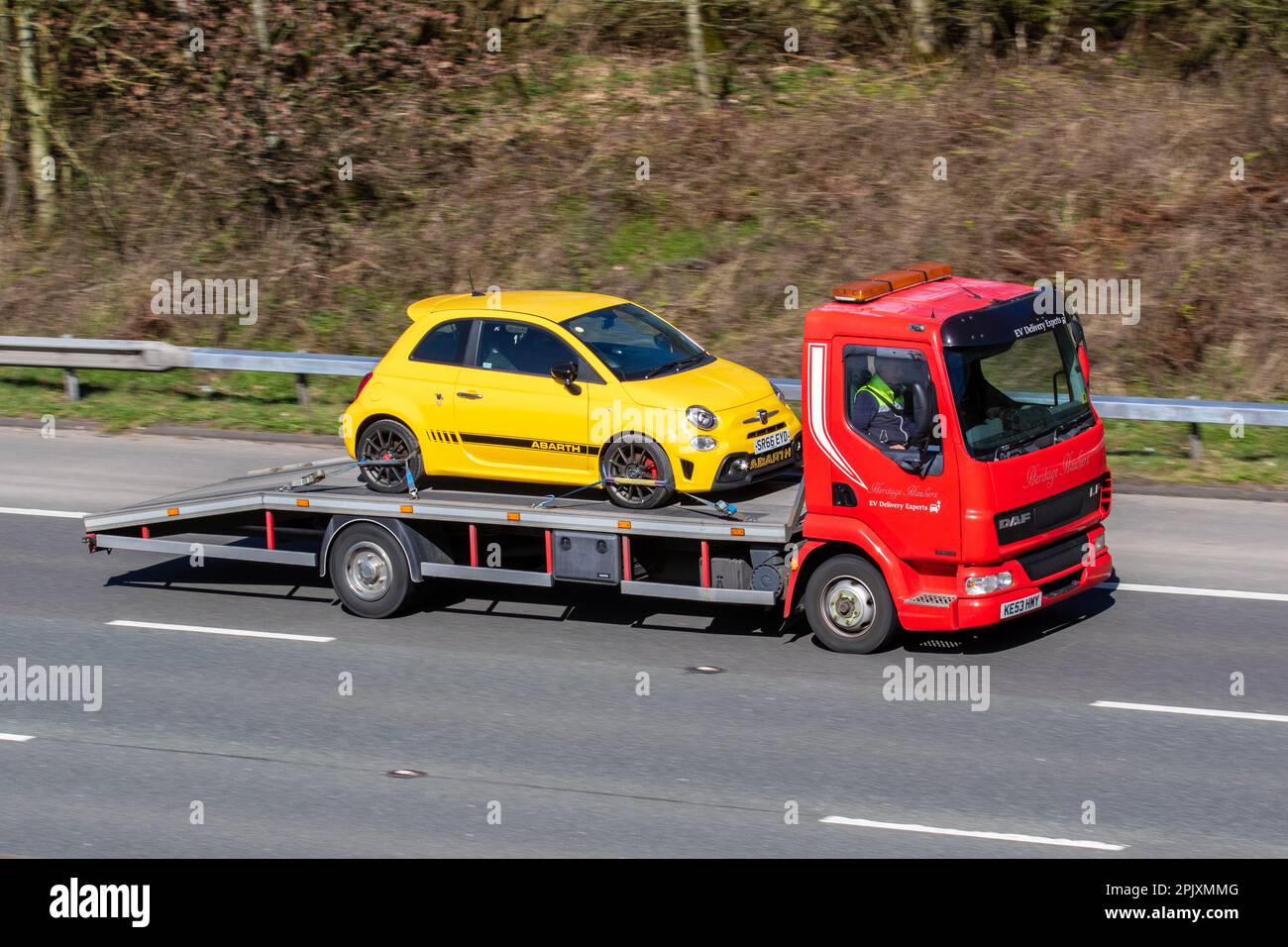 Heritage Hauliers, EV Car Delivery Experts  Red DAF FA LF45.180 45.170 DAY 5880cc Van carrying yellow 2017 FIAT ABARTH 1368cc Petrol 5 speed manual; travelling at speed on the M6 motorway in Greater Manchester, UK Stock Photo
