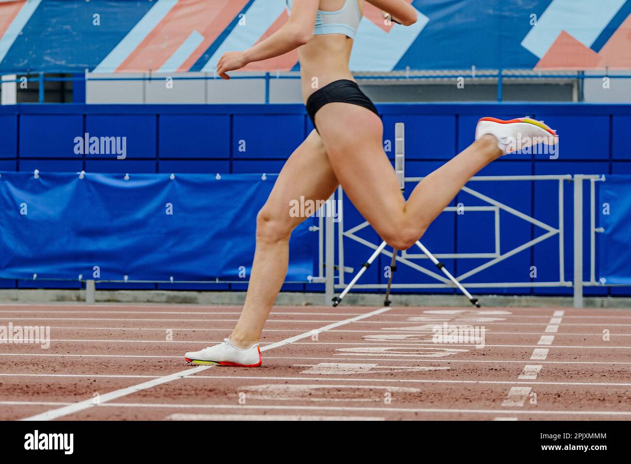 female athlete crosses finish line sprint race, summer athletics championships at stadium, legs woman runner Stock Photo