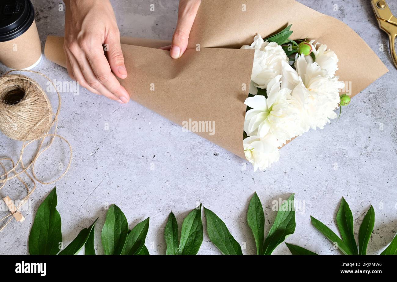 Florist makes a bouquet.a woman makes a bouquet of peonies, a bouquet of kraft paper., pruning flowers, stylite makes a bouquet Stock Photo