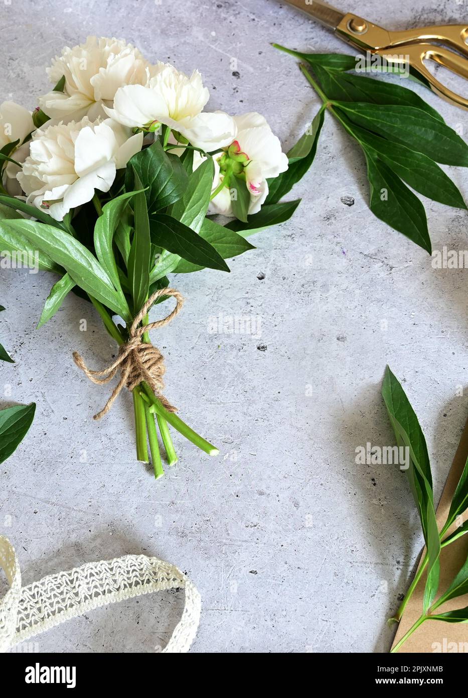 Florist makes a bouquet.a woman makes a bouquet of peonies, a bouquet of kraft paper., pruning flowers, stylite makes a bouquet Stock Photo
