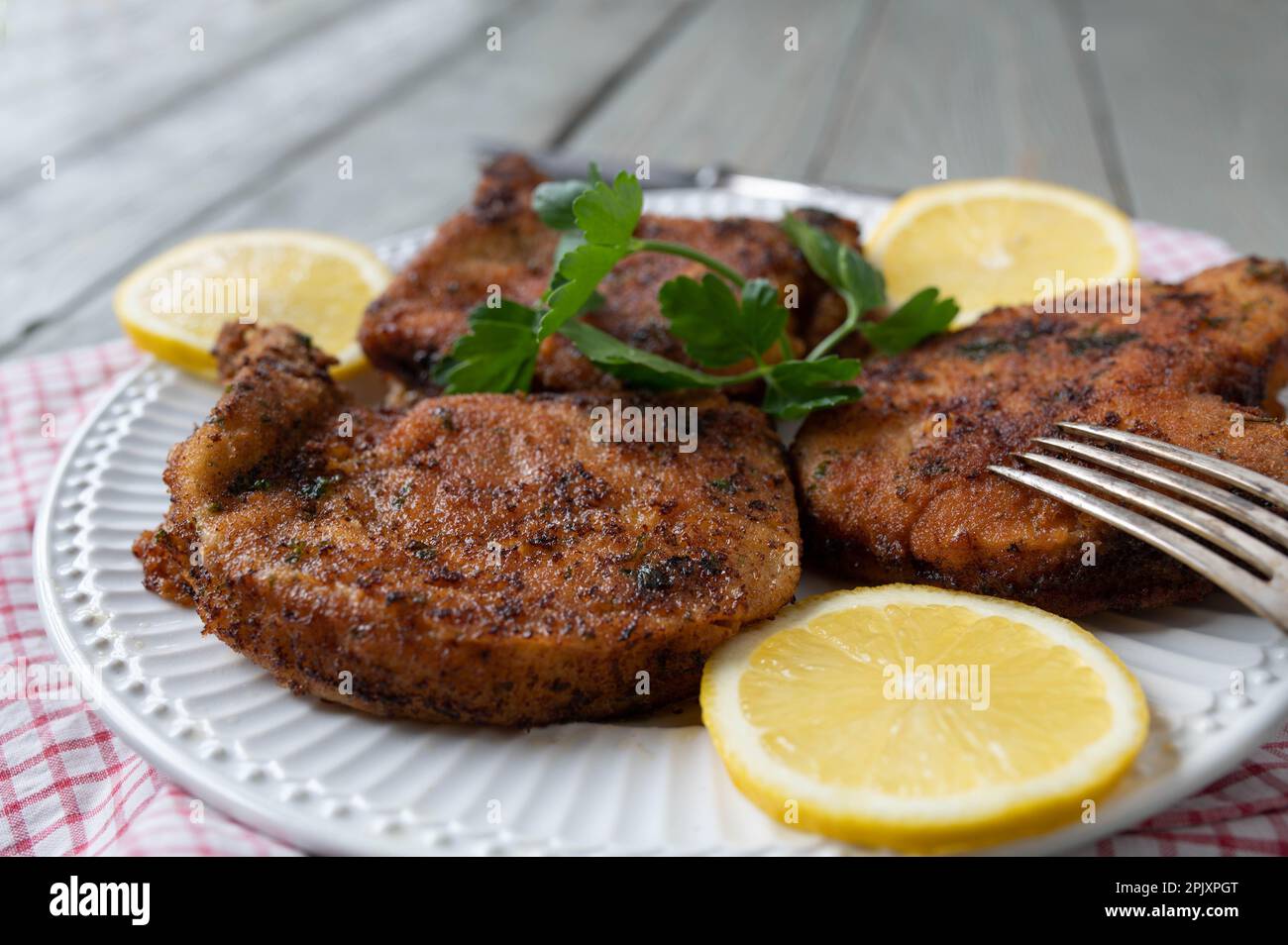 Breaded pork chops with parmesan, parsley crust on a plate with lemon. Stock Photo