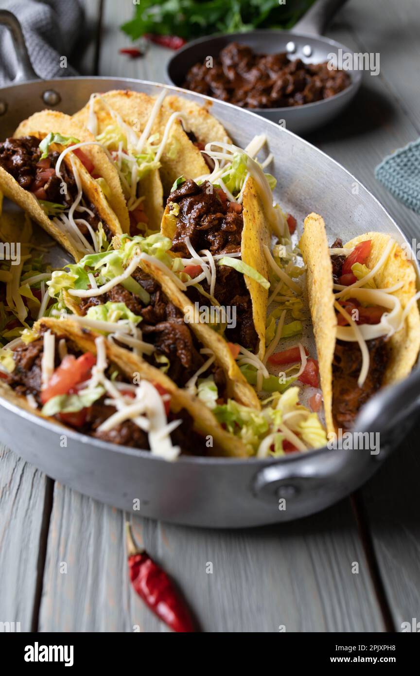 Tacos with slow cooked mexican beef, cheese, tomatoes and lettuce on