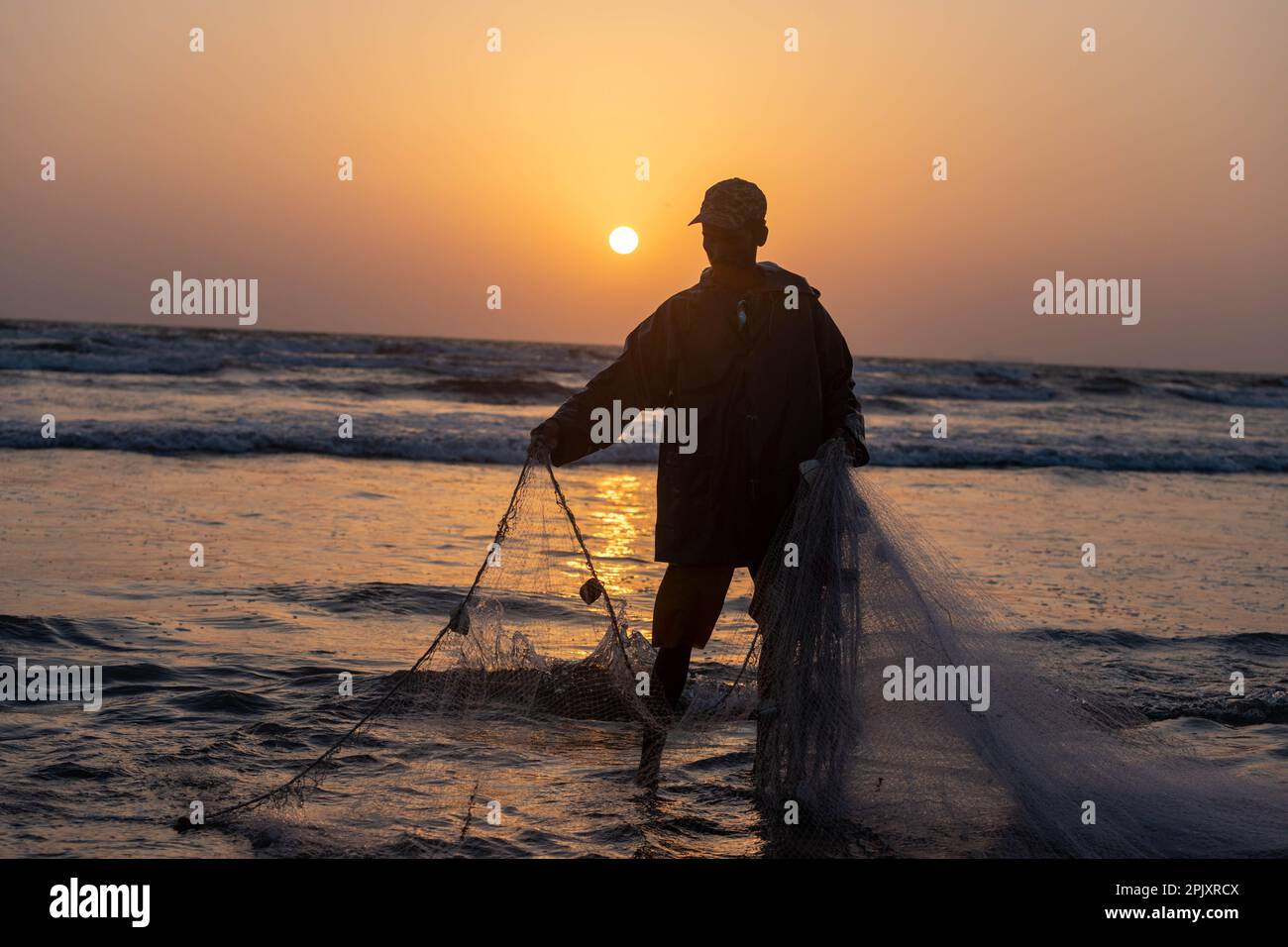 karachi pakistan 2021, a fisherman pulling fishing net to catch fish, at sea view in evening