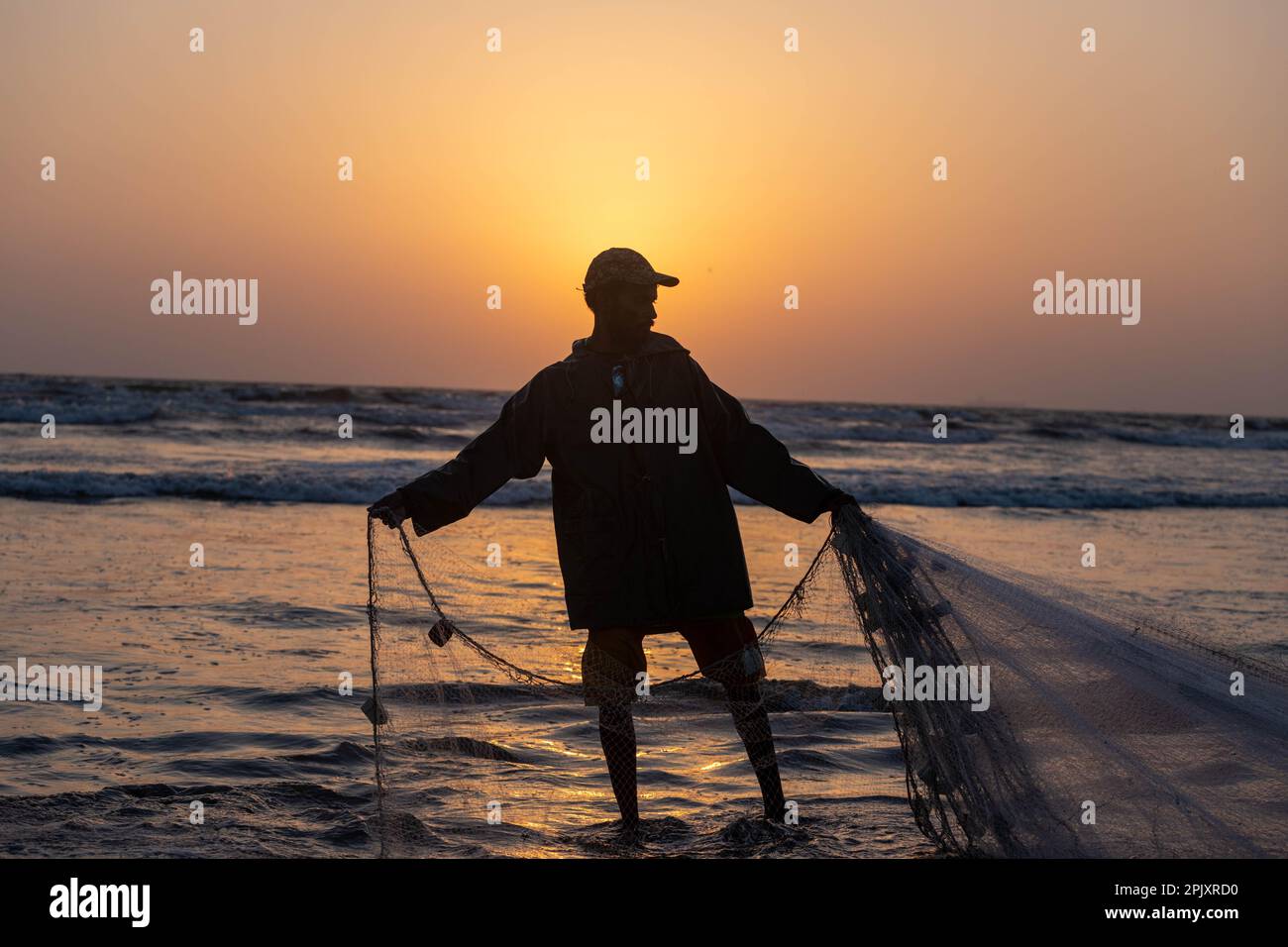 karachi pakistan 2021, a fisherman pulling fishing net to catch fish, at sea view in evening