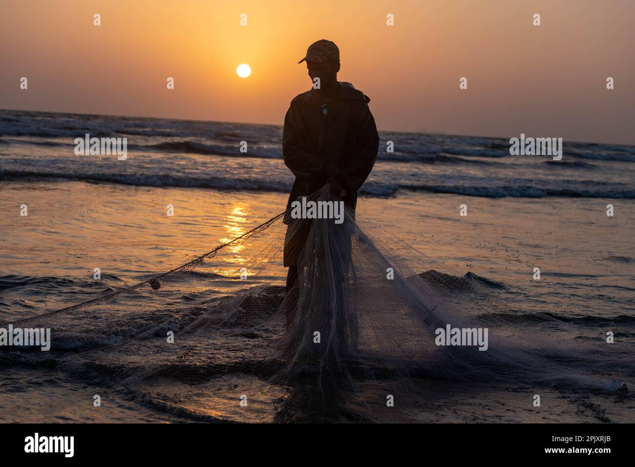 karachi pakistan 2021, a fisherman pulling fishing net to catch fish, at sea view in evening