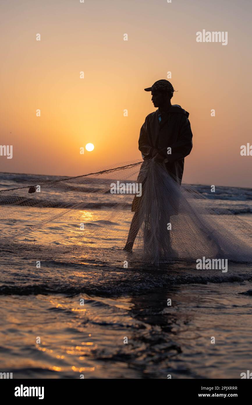 karachi pakistan 2021, a fisherman pulling fishing net to catch fish, at sea view in evening