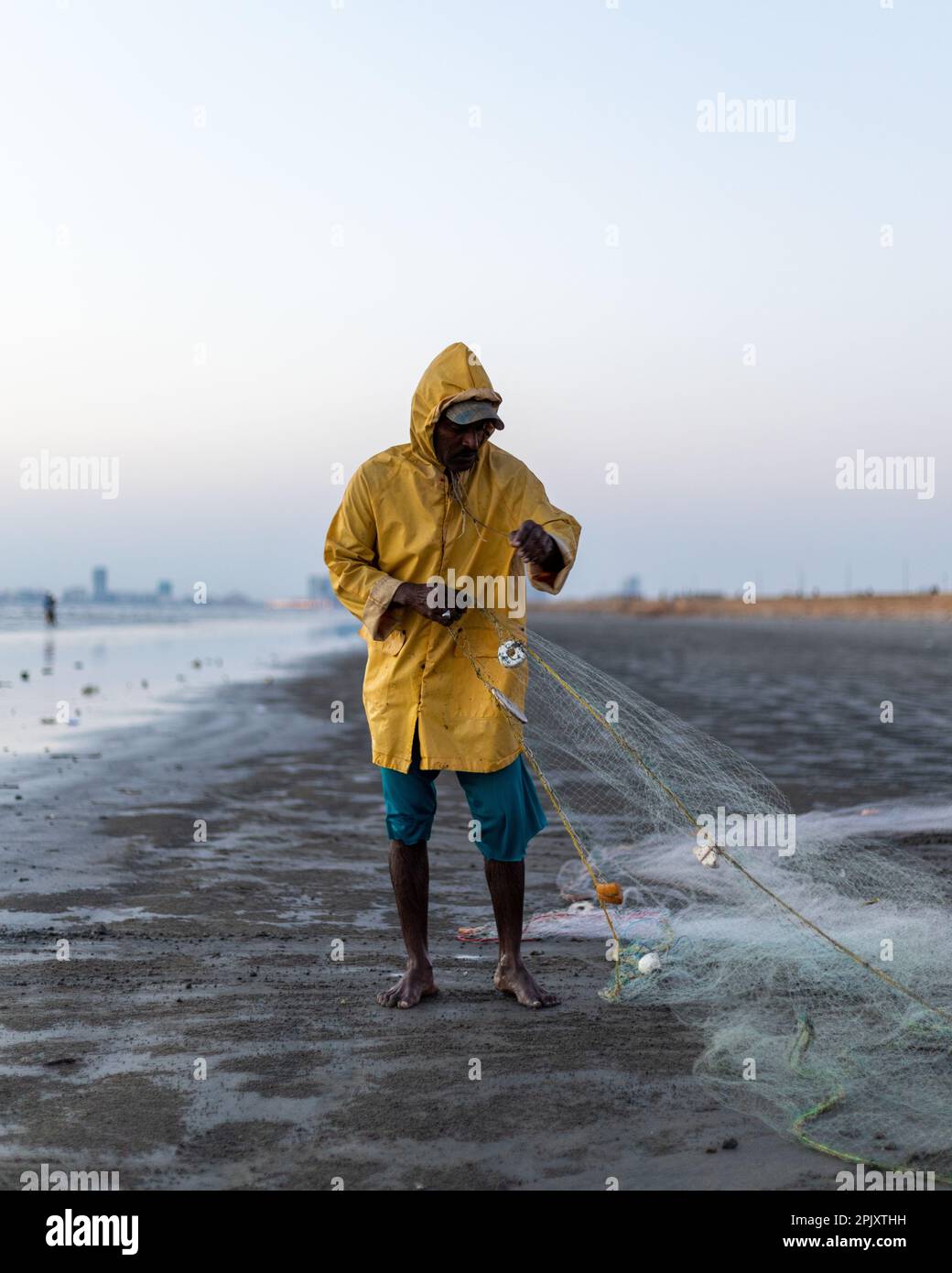 https://c8.alamy.com/comp/2PJXTHH/karachi-pakistan-2021-a-fisherman-wearing-yellow-jacket-preparing-fishing-net-for-fishing-at-sea-view-in-evening-time-2PJXTHH.jpg