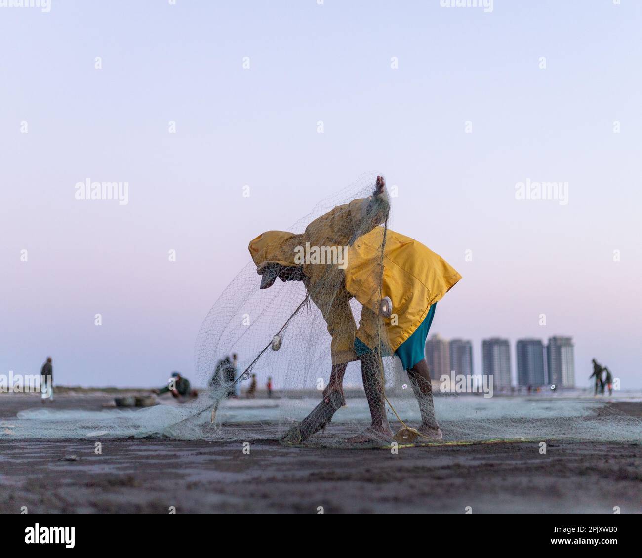 karachi pakistan 2021, a fisherman wearing yellow jacket preparing