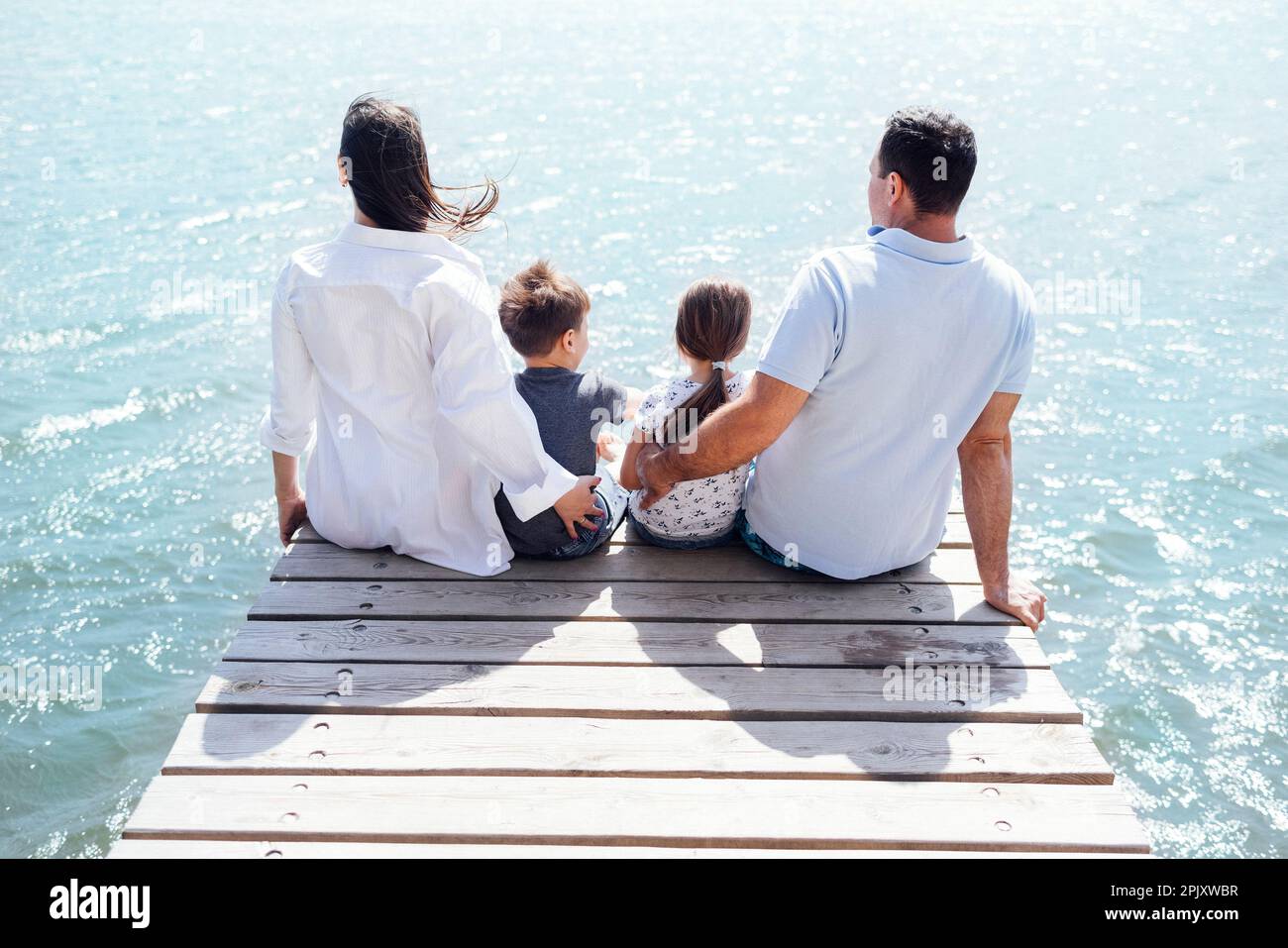 Happy family on wooden bridge against the backdrop of the sea or lake ...
