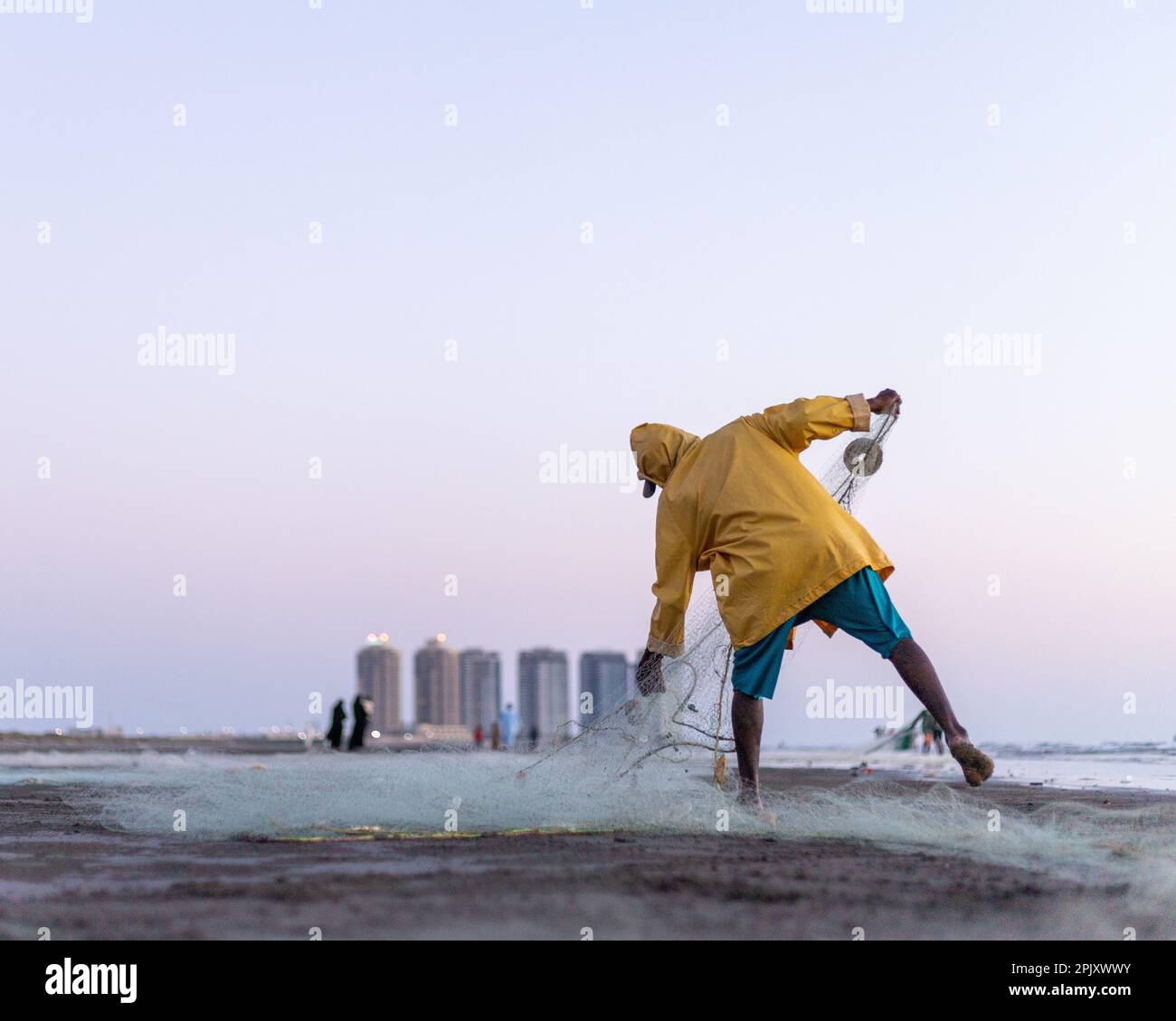 karachi pakistan 2021, a fisherman wearing yellow jacket preparing