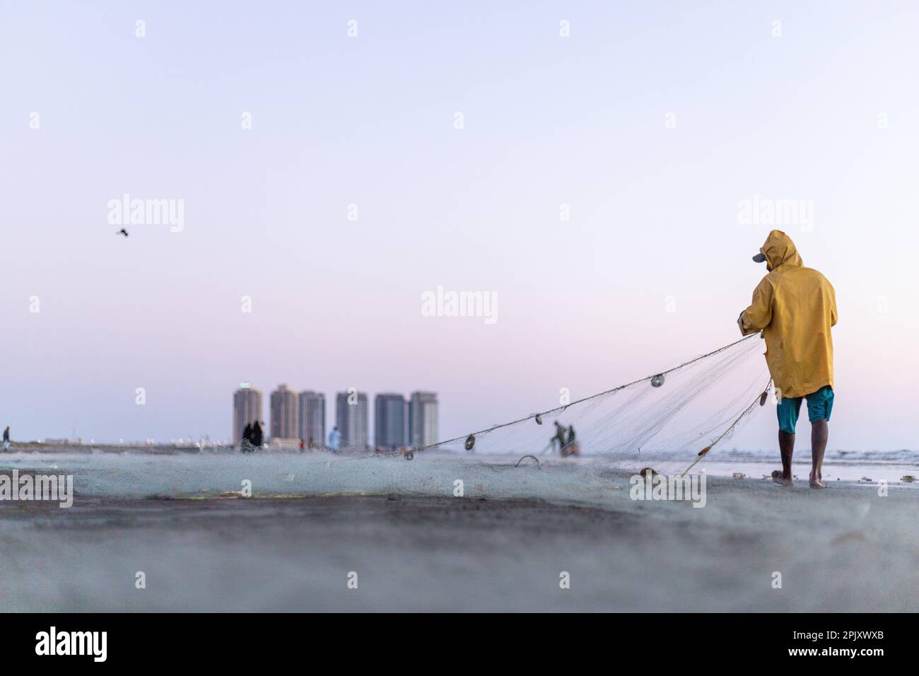 karachi pakistan 2021, a fisherman wearing yellow jacket preparing